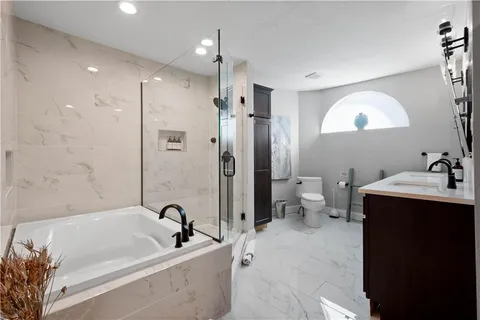 a bathroom with a tub sink toilet and a mirror