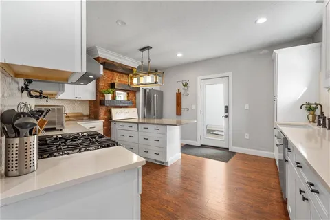 a kitchen with stainless steel appliances a stove a sink wooden floor and cabinets
