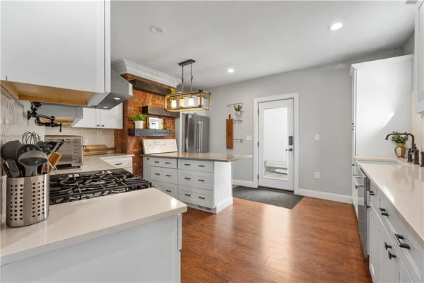 a kitchen with stainless steel appliances a stove a sink wooden floor and cabinets