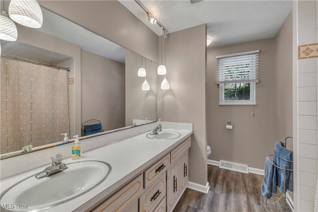 4090 Ridgeview Road Cleveland, OH 44144 - Photo 15 of 40 Bathroom featuring double vanity, wood finished floors, a textured ceiling, and a shower with curtain