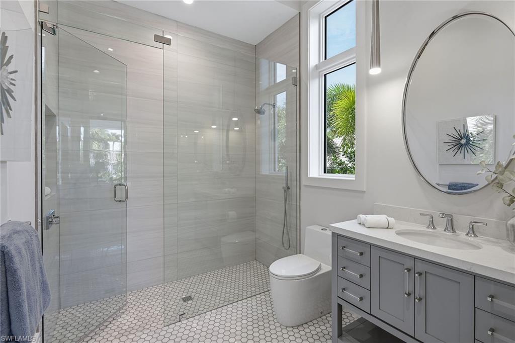 529 Neapolitan Way Naples, FL 34103 - Photo 18 of 26 a bathroom with a double vanity sink toilet and shower