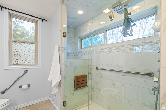 460 Omni Point Road Central Valley, UT 84754 - Photo 41 of 101 Frameless glass shower enclosure featuring marble-look tile, a mosaic accent band, a built-in wooden bench, and a rain shower head