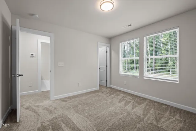 a view of an empty room with wooden floor and a ceiling fan
