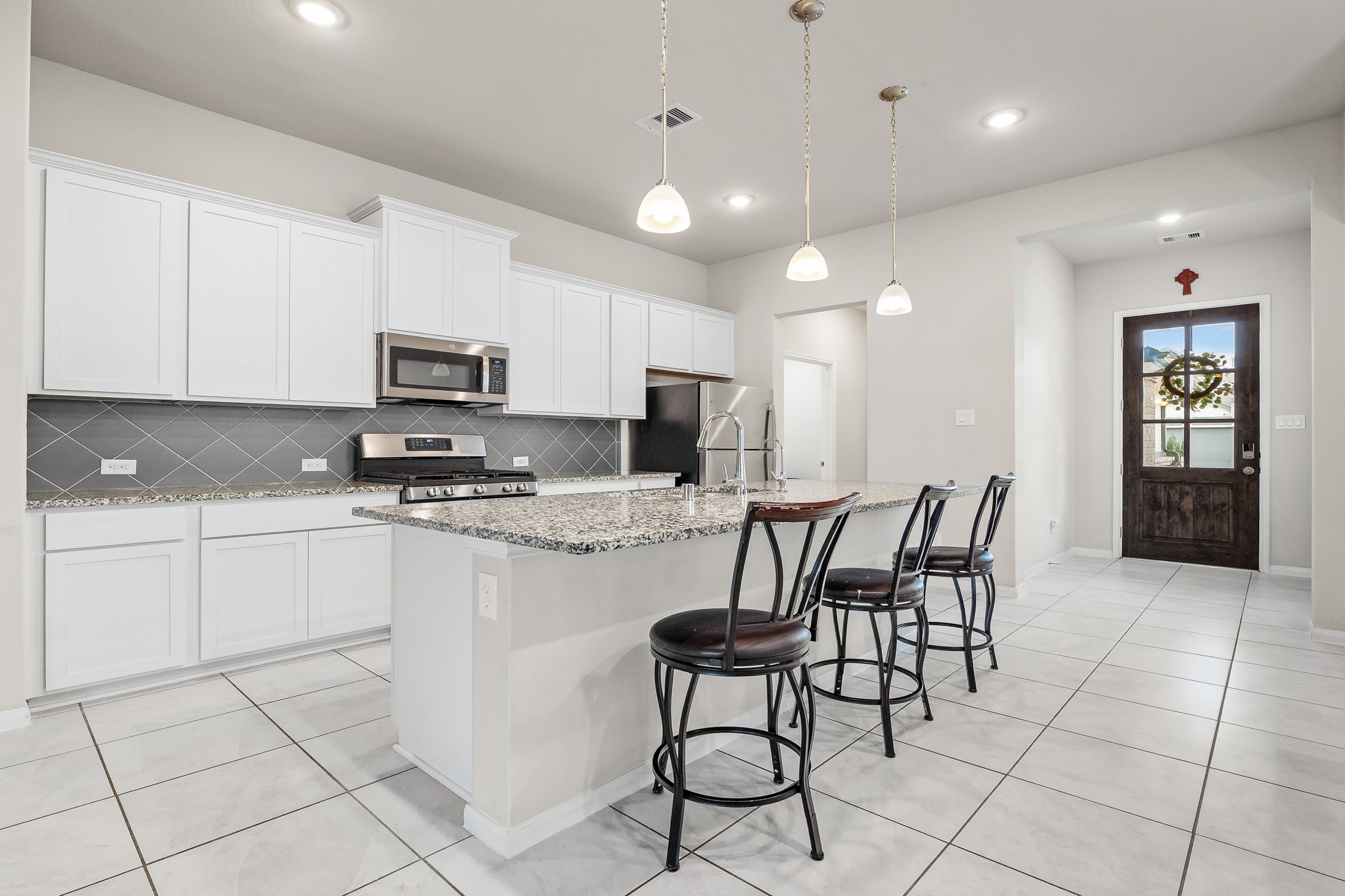 3722 Amoroso Drive Rosharon, TX 77583 - Photo 9 of 27 a kitchen with stainless steel appliances granite countertop a stove a sink a microwave a dining table and chairs