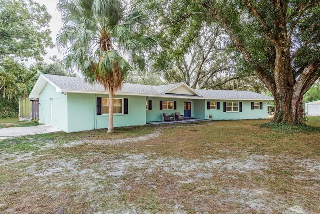an aerial view of residential house with outdoor space and trees all around