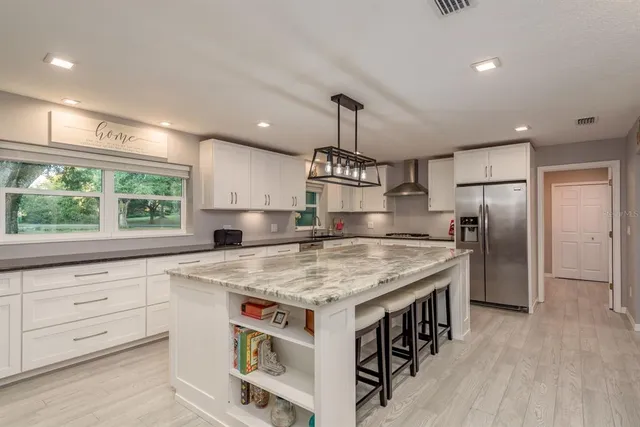 a large kitchen with stainless steel appliances granite countertop a stove a sink and a refrigerator