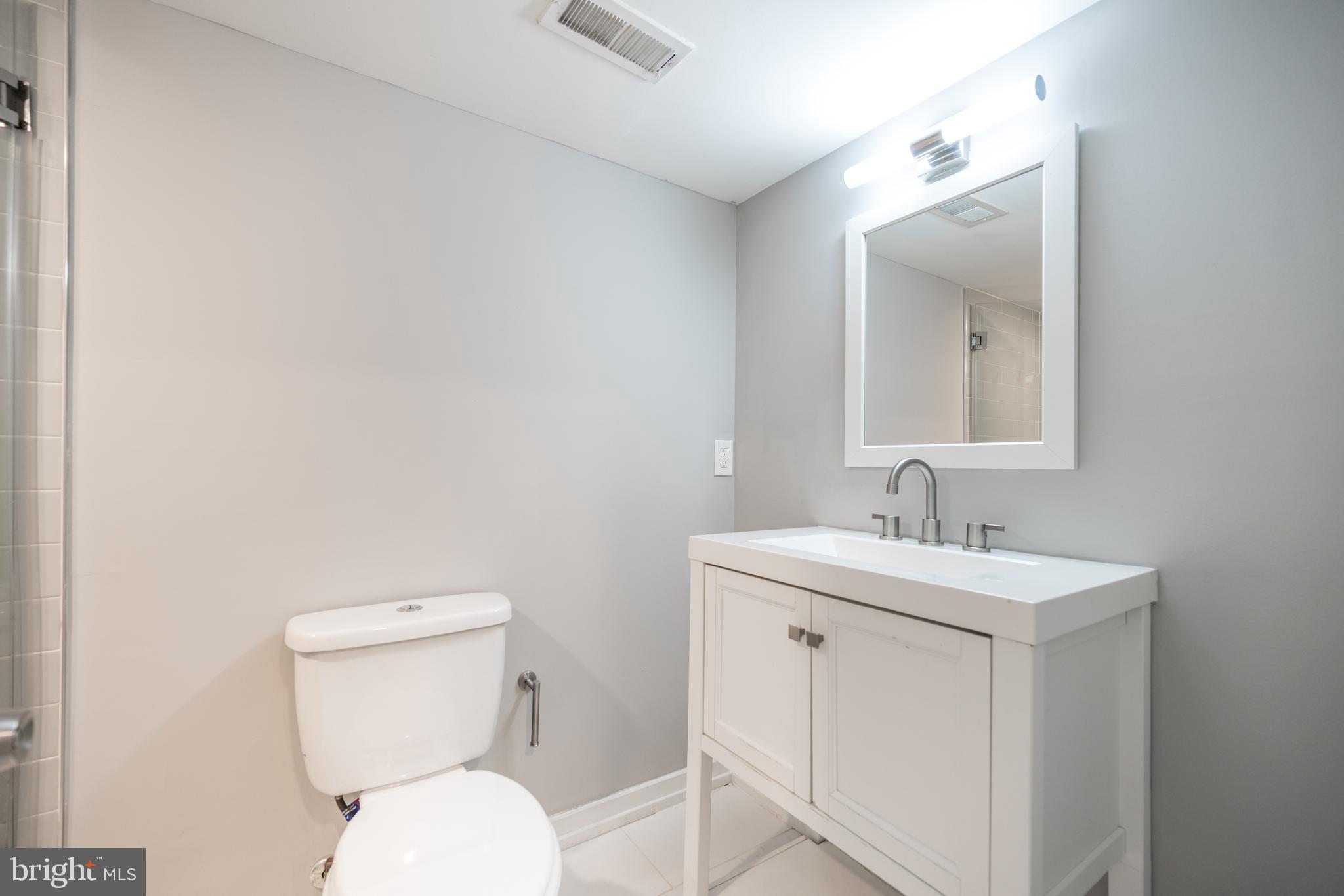 2428 Jasper Street, Unit A Philadelphia, PA 19125 - Photo 13 of 26 a bathroom with a toilet a sink and mirror