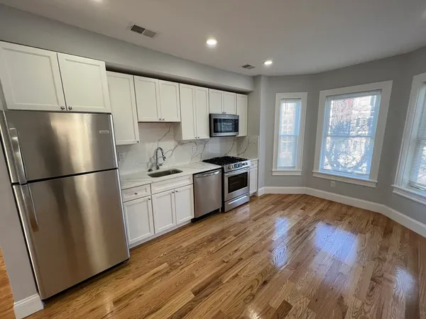 a kitchen with a refrigerator a stove top oven a sink and cabinets with wooden floor