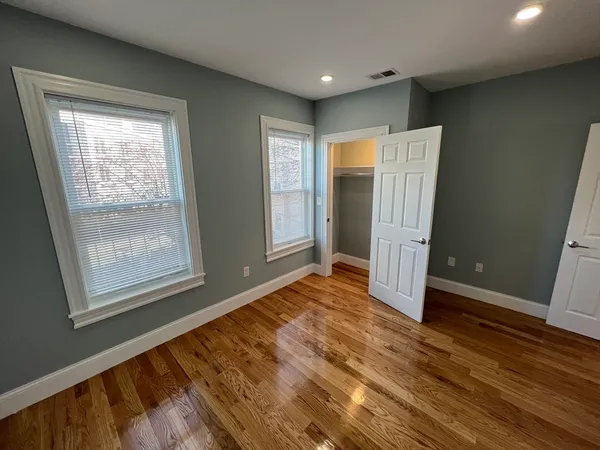 an empty room with wooden floor and windows