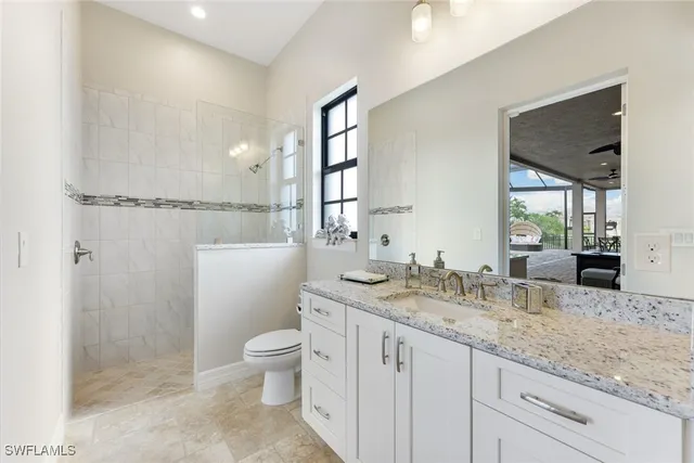a bathroom with a granite countertop sink mirror vanity and toilet