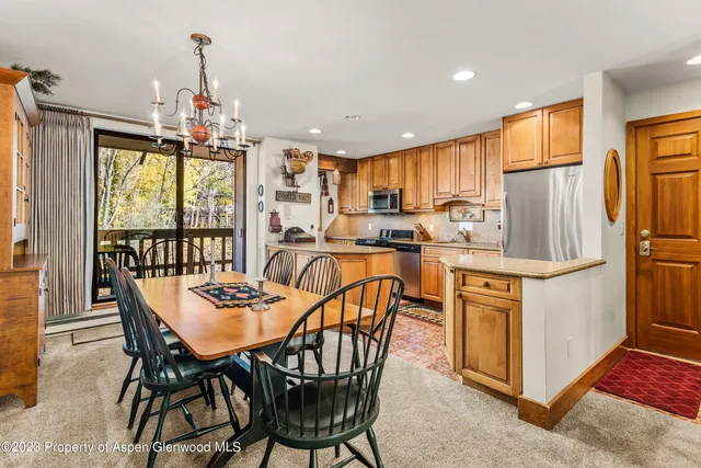 a kitchen with stainless steel appliances granite countertop a table chairs and a refrigerator