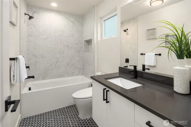 a bathroom with a granite countertop bathtub sink vanity mirror and toilet
