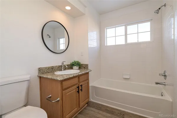 a bathroom with a granite countertop toilet a sink and a bathtub