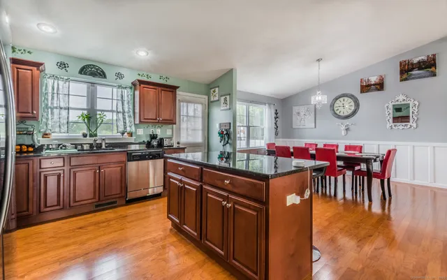 a kitchen with stainless steel appliances granite countertop a stove a sink dishwasher a dining table and chairs with wooden floor