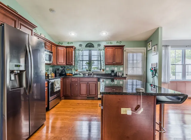 a kitchen with stainless steel appliances granite countertop a refrigerator a stove and a sink