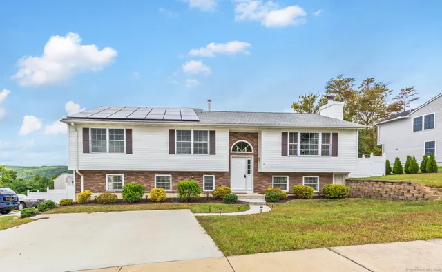a front view of a house with a garden and trees