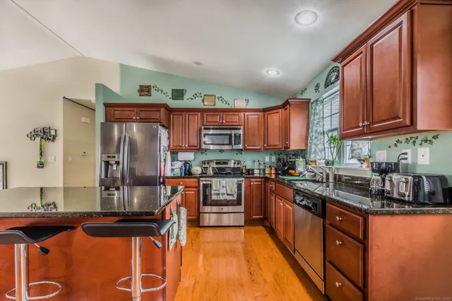 a kitchen with stainless steel appliances granite countertop a refrigerator a stove and a sink