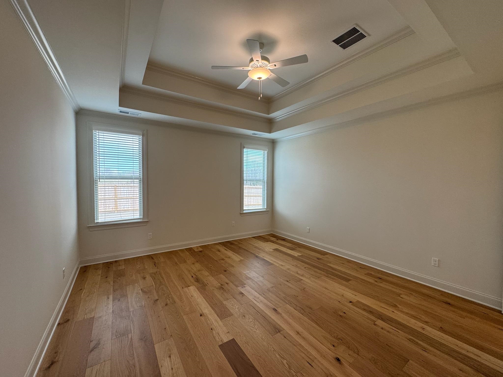 11512 Sunsparkler Way Collierville, TN 38017 - Photo 21 of 40 Unfurnished room featuring light wood-style flooring, a ceiling fan, ornamental molding, and a tray ceiling