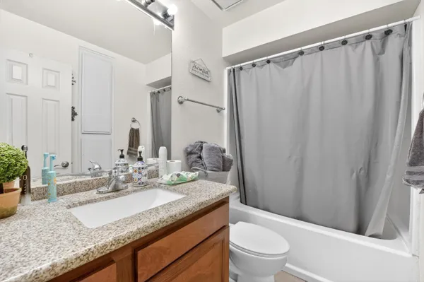 a bathroom with a granite countertop sink a toilet and a mirror