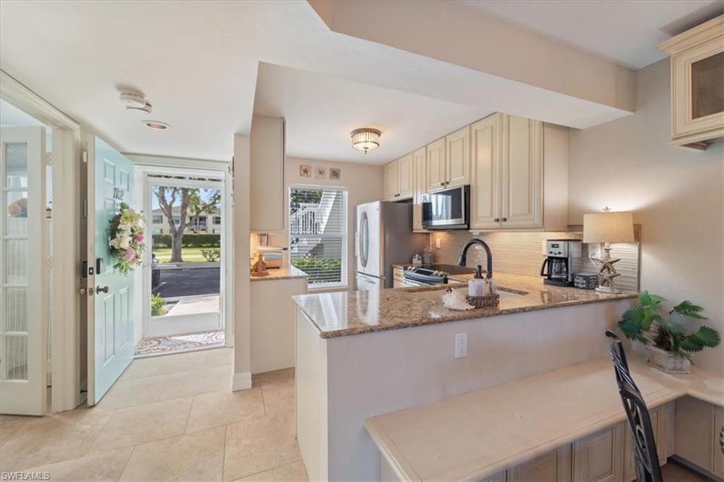 1375 Mainsail Drive, Unit 1702 Naples, FL 34114 - Photo 8 of 38 a dining hall with stainless steel appliances granite countertop a refrigerator a sink a stove a dining table and chairs