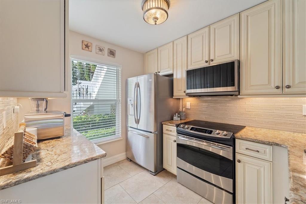 1375 Mainsail Drive, Unit 1702 Naples, FL 34114 - Photo 10 of 38 a kitchen with granite countertop a refrigerator stove and microwave