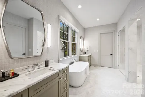 a spacious bathroom with a double vanity sink mirror and bathtub