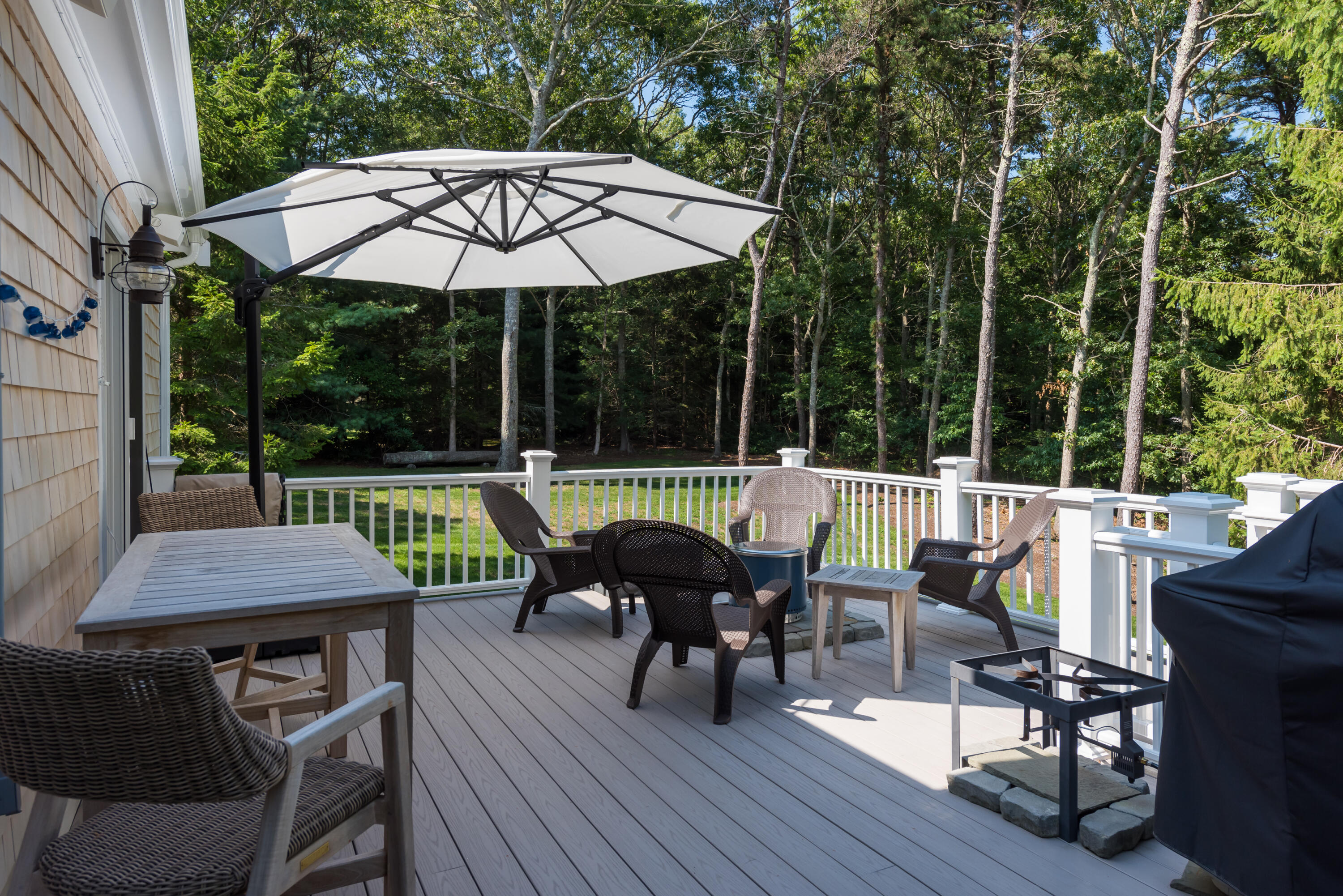 68 Tupelo Road Marstons Mills, MA 02648 - Photo 13 of 29 a view of a patio with a dining table and chairs under an umbrella with wooden floor