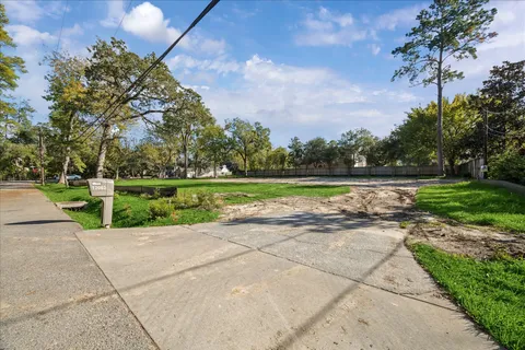 a view of a park with plants and a bench with wooden fence