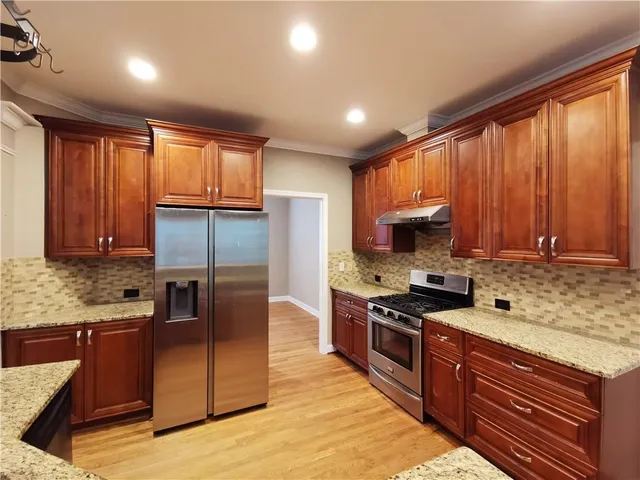 a kitchen with stainless steel appliances granite countertop a stove top oven a sink dishwasher a refrigerator and cabinets with wooden floor