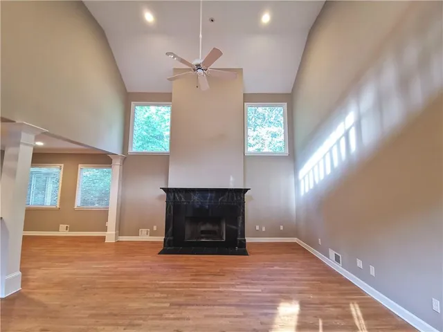 a view of an empty room with wooden floor and a fireplace