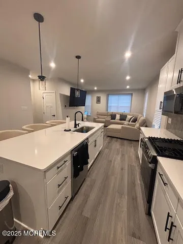 a kitchen with a stove a sink a refrigerator and chairs