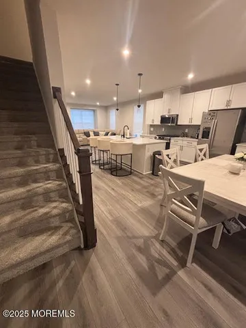 a living room with couches and kitchen view with wooden floor