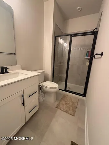 a bathroom with a sink a toilet a mirror and shower