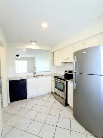 a kitchen with granite countertop a refrigerator and a stove top oven