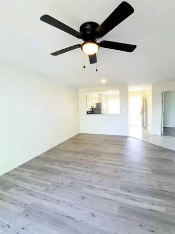 an empty room with wooden floor ceiling fan and windows