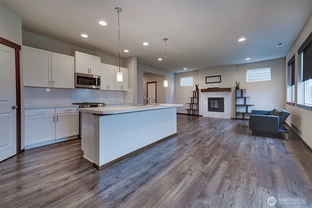 a kitchen with stainless steel appliances granite countertop a stove top oven a sink dishwasher and a refrigerator with wooden floor