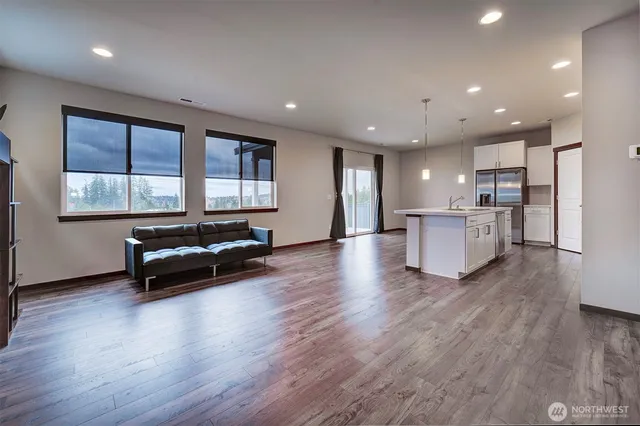 a living room with stainless steel appliances kitchen island hardwood floor and a sink