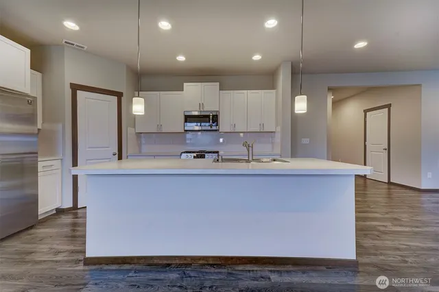 a large kitchen with stainless steel appliances a large counter top a sink and a refrigerator