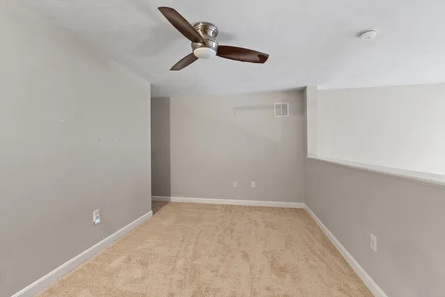 an empty room with a ceiling fan and carpet