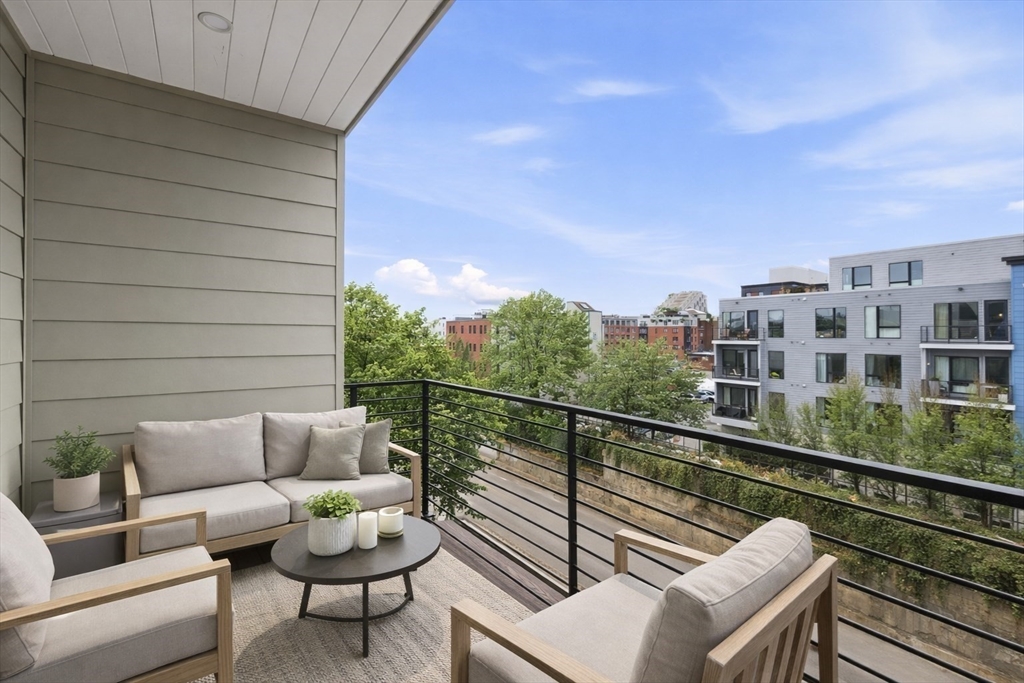 118 B Street, Unit 401 Boston, MA 02127 - Photo 7 of 9 a balcony with wooden floor and glass top table