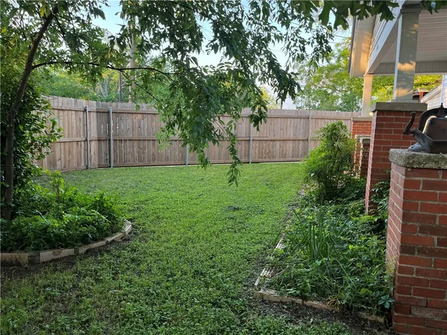 a view of a backyard with potted plants and large tree