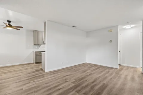 a view of empty room with wooden floor and bathroom