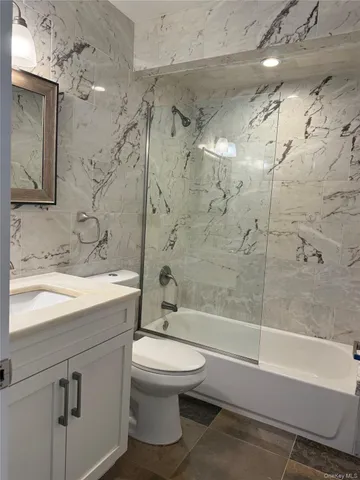 a bathroom with a bathtub shower sink vanity and toilet