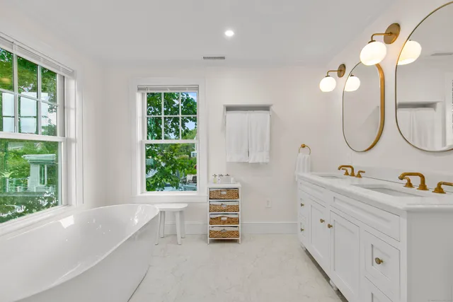 a bathroom with a double vanity sink a two mirror and a window