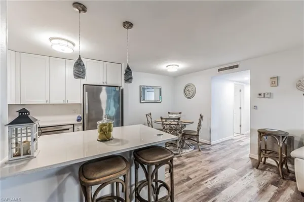a kitchen with stainless steel appliances a dining table chairs and wooden floor