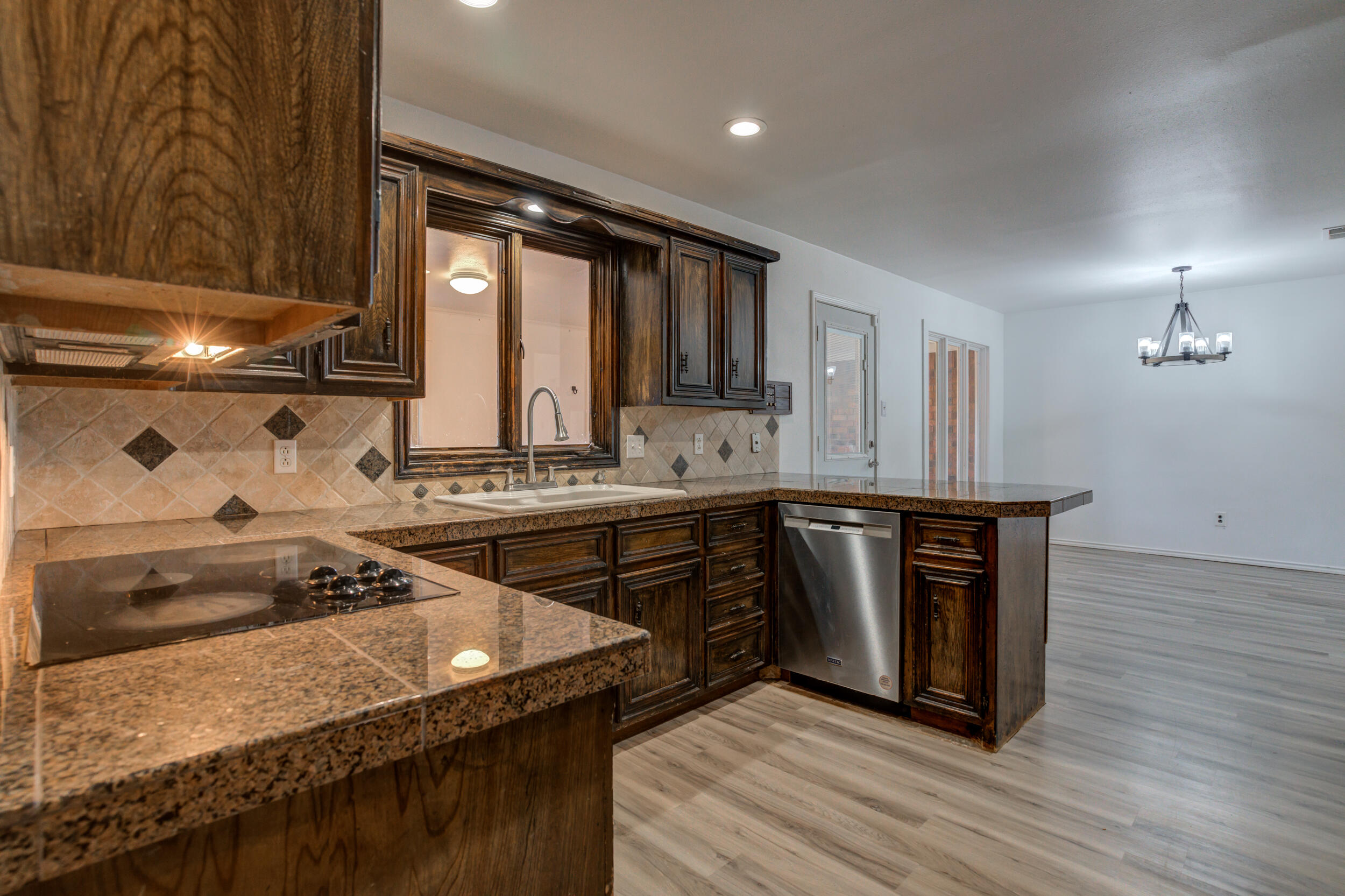 5504 73rd Street Lubbock, TX 79424 - Photo 17 of 39 a kitchen with kitchen island granite countertop a sink cabinets and wooden floor