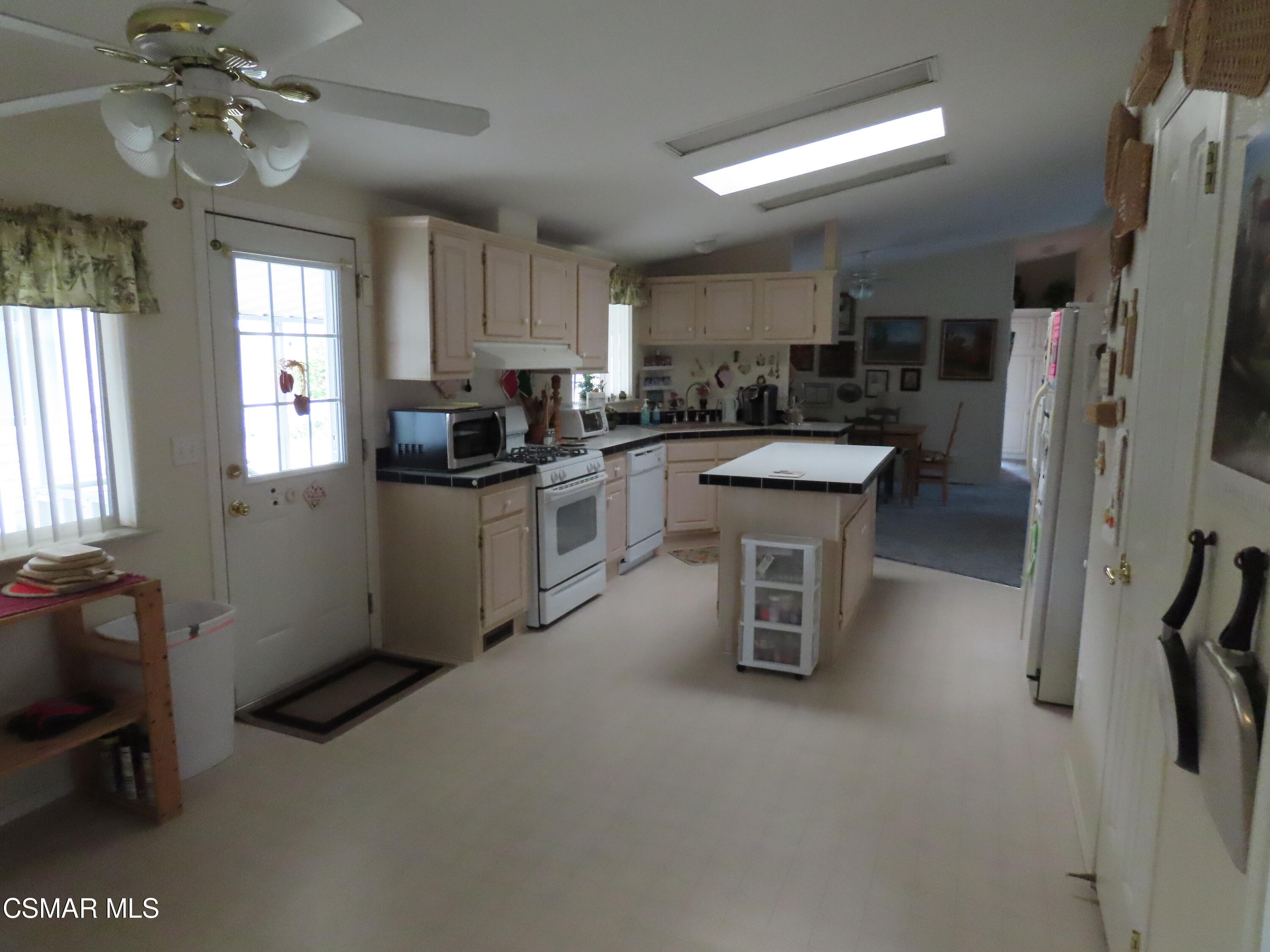 250 East Telegraph Road, Unit 58 Fillmore, CA 93015 - Photo 5 of 29 a kitchen with stainless steel appliances granite countertop a refrigerator a sink dishwasher a stove and a dining table with wooden floor