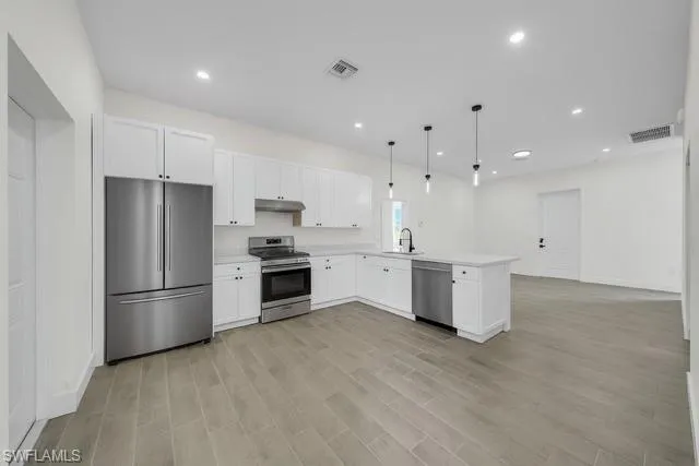a kitchen with kitchen island a sink stainless steel appliances and cabinets