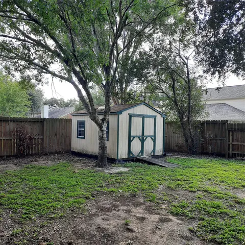 a view of a house with a yard and large trees