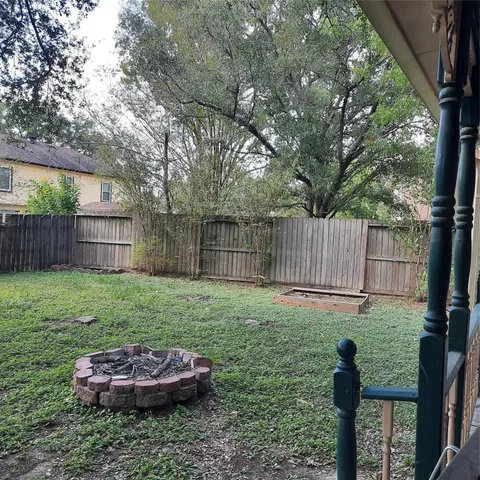 a view of a backyard with wooden fence and a large tree